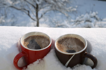 Two coffee mugs in snow

Foreground with two cups of hot steamy coffee buried in snow, just...