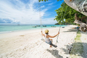 Beautiful woman swinging on a Tropical beach on Koh Lipe island. Thailand.