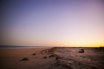 geländwagen am stand in australien beim sonnenuntergang