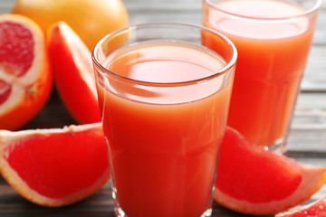 Glass of grapefruit juice and fresh fruits on wooden background