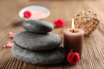 Fototapeta na wymiar Relax set which include aroma candles, flowers, petals and pebbles on wooden background
