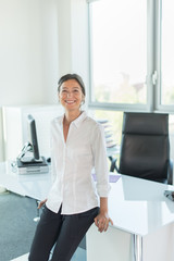 Obraz na płótnie Canvas business woman leaning against her glass desk, luminous office 