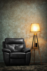 Black leather chair and lamp on grey wall background