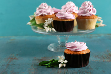 Tasty cupcakes on stand, on color wooden background