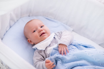 Baby boy in a crib under knitted blanket