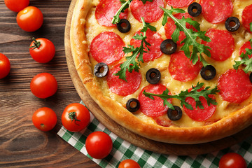 Tasty pizza with salami on decorated wooden table