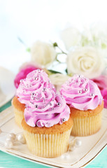 Tasty cupcakes on plate, on color wooden background