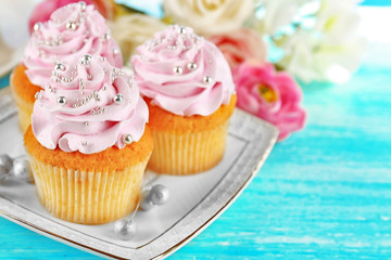 Cake with sugar paste flowers and cupcakes, on light background
