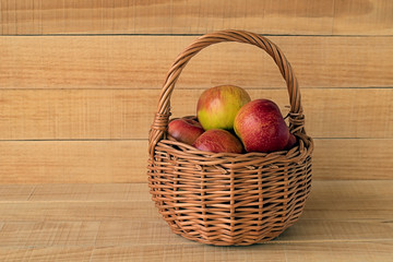 Apples.  Red ripe apples in a wicker basket on a wooden background.