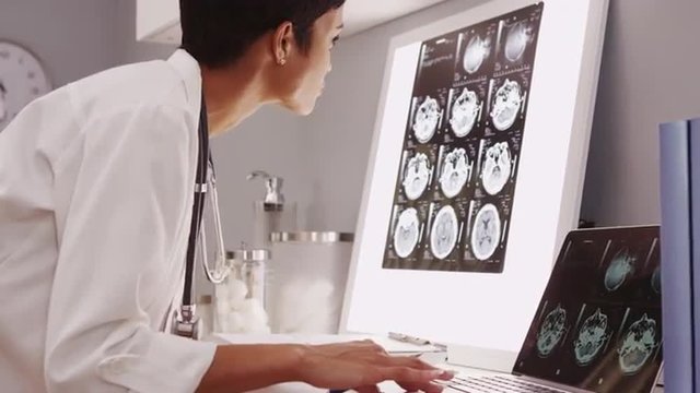Young female medical assistant looking at x-ray scans