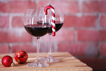 Two glasses of wine with christmas toys on wall background