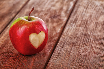 Apple with heart on wooden table