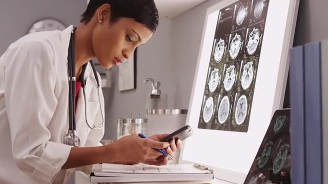 Young attractive doctor texting results of brain scans
