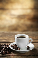 Cup of coffee and coffee grains on wooden background