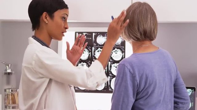 Black female doctor showing senior patient x-ray film