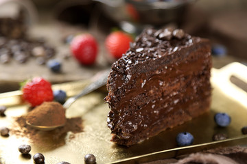 Chocolate cake with chocolate cream and fresh berries on tray, on wooden background