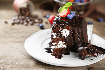 Chocolate cake with cream and fresh berries on plate, on wooden background