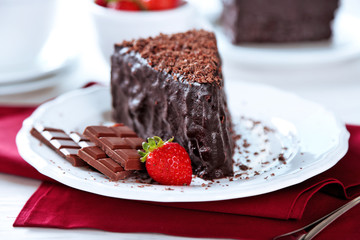 Chocolate cake with chocolate cream and fresh strawberries on plate, on light background