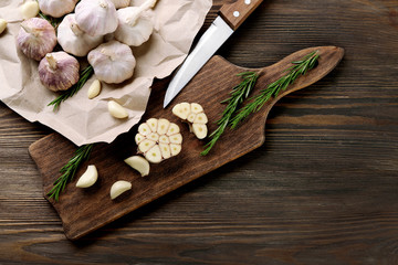 Composition of garlic and rosemary with knife on the kitchen board, close up