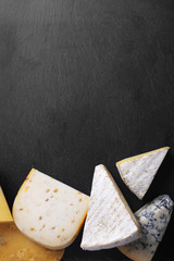 Different kinds of cheese on black background, copy space