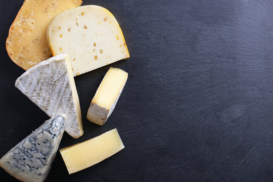 Different kinds of cheese on black background, copy space