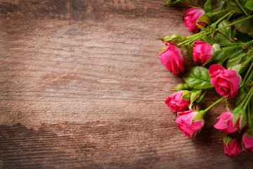 Naklejka na ściany i meble Beautiful bouquet of pink little roses on wooden background, copy space