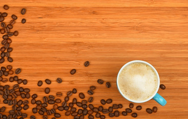 Coffee cup and beans over wood background