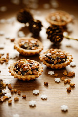 Chocolate cashew nut small tarts on wooden table. A delicious Christmas dessert