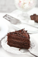 Sliced chocolate cake on wooden table, on light background