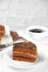 Sliced chocolate cake on wooden table, on light background