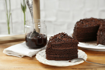 Sliced chocolate cake on wooden table, on light background