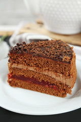 Sliced chocolate cake on plate, on wooden table  background