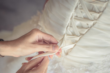Obraz na płótnie Canvas Bridesmaid helps the bride to wear dress
