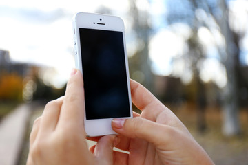Woman holding smartphone outside