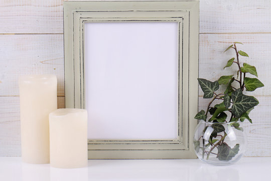 Empty picture frame with copy space blank on white rustic background and Ivy plant.  Scandinavian style home interior decoration