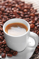 Cup of coffee and coffee grains on dark background