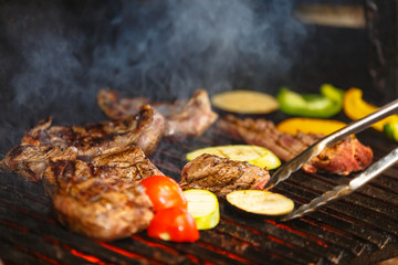 Beef steaks with tomatoes and other vegetables are fried on a charcoal grill
