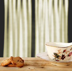 Chocolate Cookies and tea put on Wooden with white curtain background.