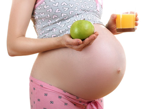 a pregnant woman in pyjamas holding a green Apple isolated on white background