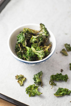 Homemade curly kale chips in small bowl. Selective focus