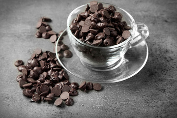 Chocolate morsels in glass mug on gray background