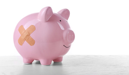 Piggy Bank with adhesive bandage wooden table, on white background