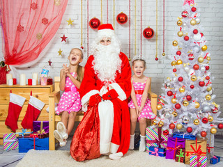 Obraz premium Happy girls and Santa Claus sitting on a bench in a Christmas setting