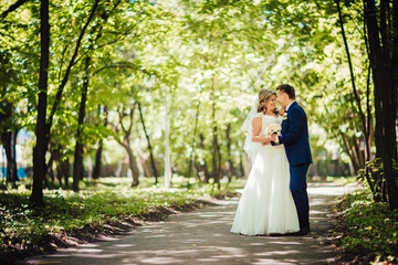 Happy couple bride and groom embracing they stand in a forest full length