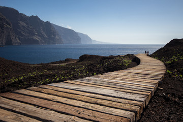 two friends / couple walking on wooden path to beach / ocean