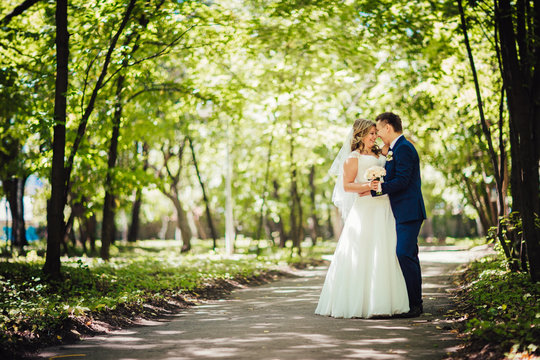 Happy couple bride and groom embracing they stand in a forest full length