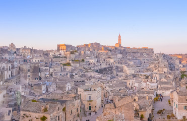 Fototapeta na wymiar panoramic view of typical stones and church of Matera and the Madonna de Idris under begin sunset sky