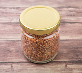 Brown millet grain seed in a mason jar over wooden background