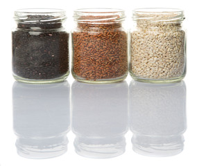 White, black and brown millet grain seed in mason jar over white background