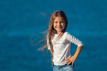 Adorable happy smiling little girl on beach vacation. jeans.